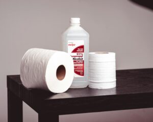 A Pair of Tissue Rolls and a Bottle of Isopropyl Alcohol on a Wooden bench