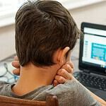 boy in gray shirt using black laptop computer