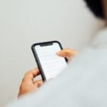 man in white top holding iPhone