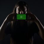 woman holding black smartphone at Whatsapp logo