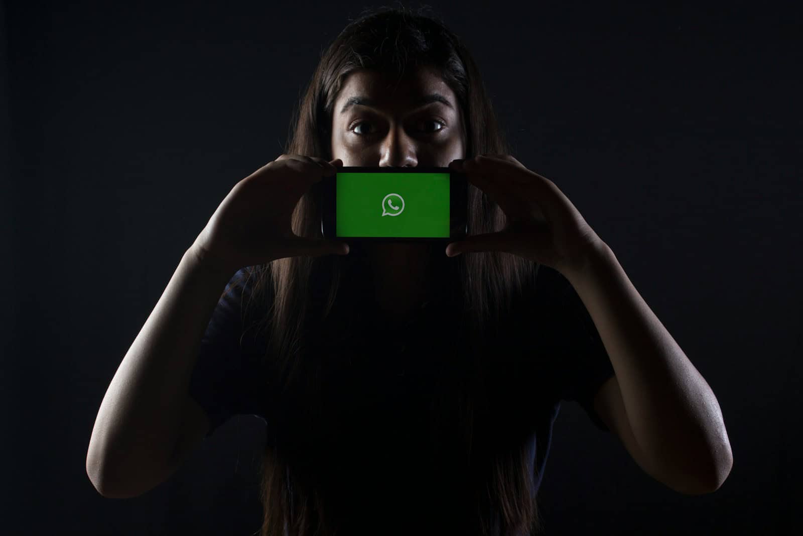 woman holding black smartphone at Whatsapp logo