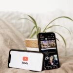 a cell phone sitting on top of a bed next to a plant