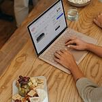 Person sitting on a table clicking on their Surface laptop