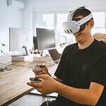 a man sitting at a desk wearing a virtual reality headset